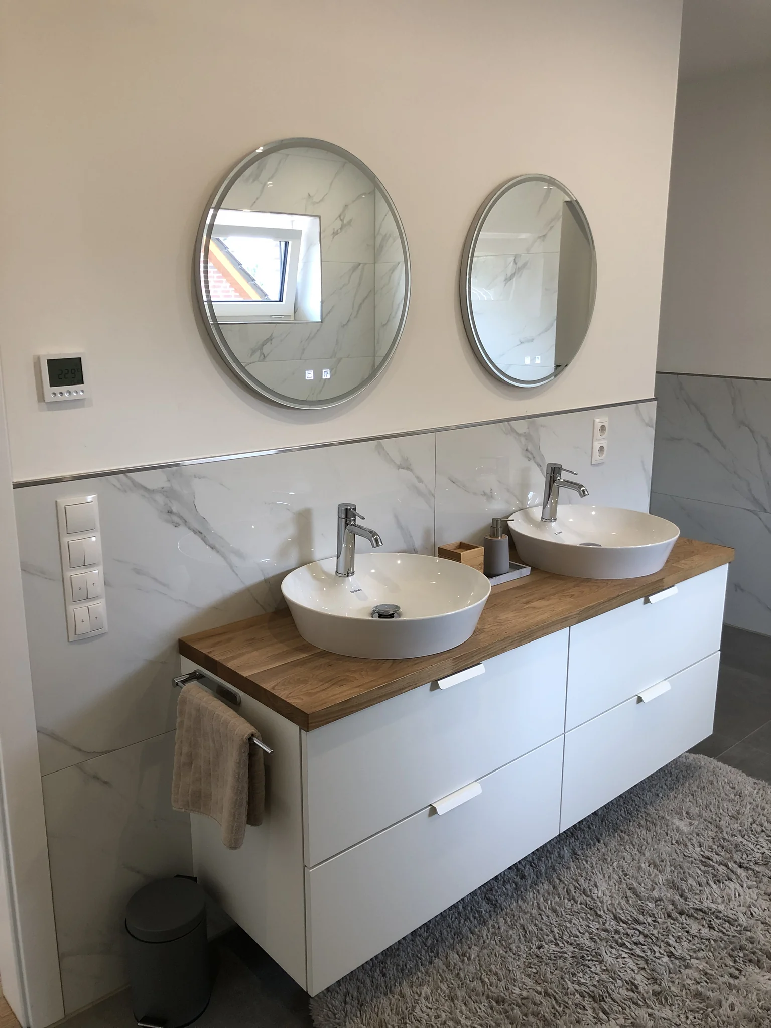 Ein schönes Badzimmer mit Holz und runden Spiegeln und einem Teppich