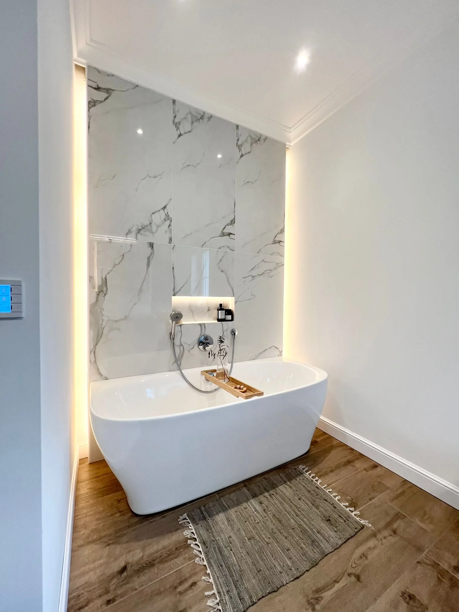 Eine helle und beleuchtete Badewanne mit Marmoroptik im Hintergrund