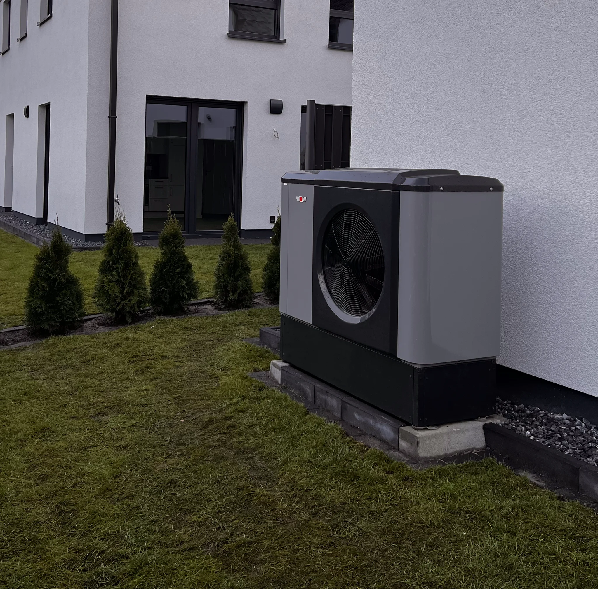 Eine moderne Wärmepumpe aufgestellt vor einem Wohnkomplex